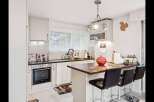 This charming kitchen boasts a modern design with sleek white cabinetry and a contrasting dark countertop.
