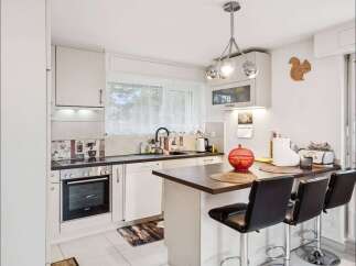 This charming kitchen boasts a modern design with sleek white cabinetry and a contrasting dark countertop.