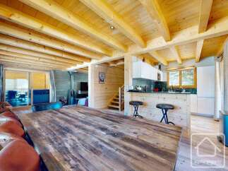 Experience the charm of this stunning property, featuring a rustic wooden dining table and a cozy living area.