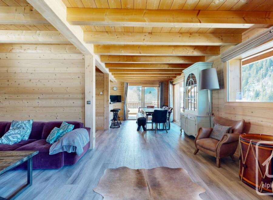 Experience the epitome of alpine living in this stunning property, boasting a warm and inviting interior with exposed wooden beams and paneling.