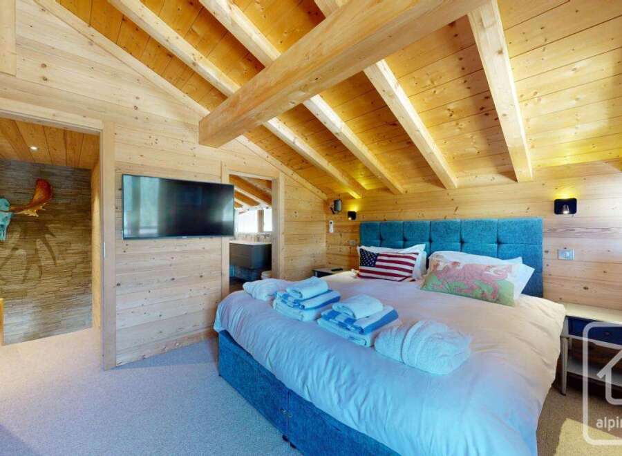 Experience the charm of this stunning property, featuring a cozy bedroom with wooden accents and a vaulted ceiling.
