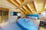 Experience the charm of this stunning property, featuring a cozy bedroom with wooden accents and a vaulted ceiling.