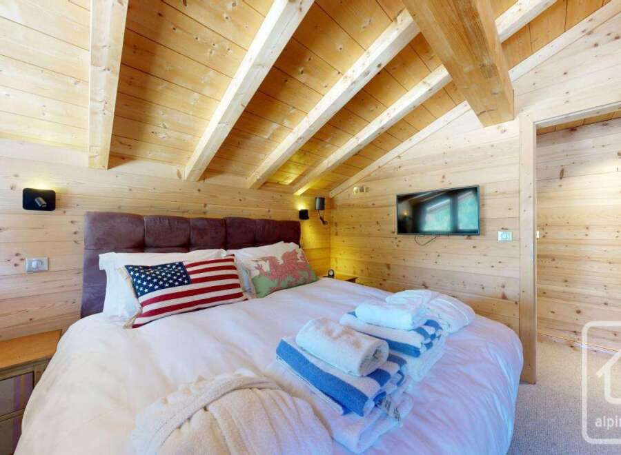 Experience the charm of this cozy bedroom featuring a rustic wooden ceiling and walls, creating a warm and inviting atmosphere.