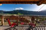 Enjoy breathtaking mountain views from this charming balcony, complete with two red chairs and a small table, perfect for morning coffee or evening relaxation.