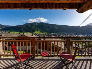 Enjoy breathtaking mountain views from this charming balcony, complete with two red chairs and a small table, perfect for morning coffee or evening relaxation.