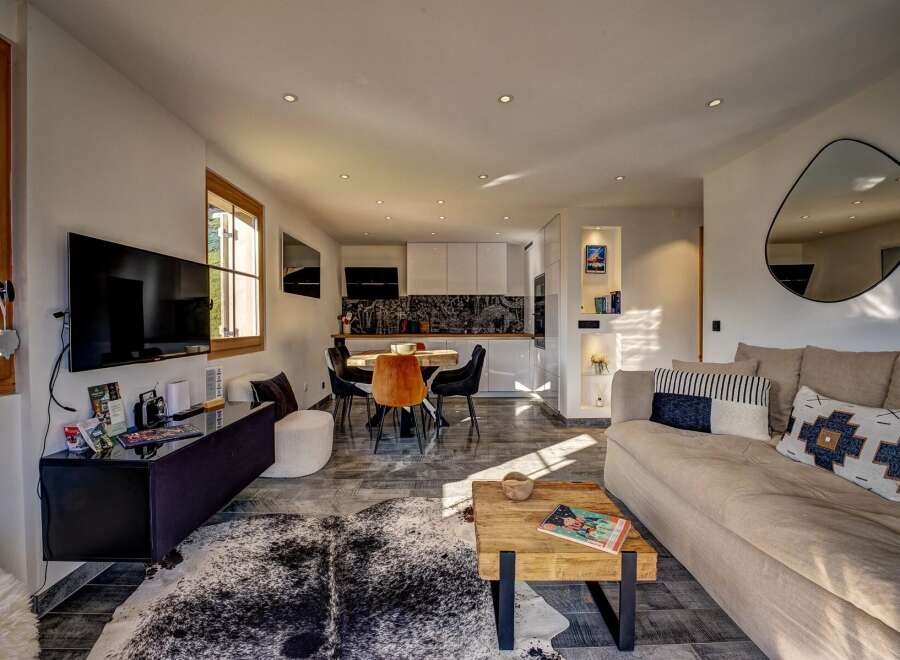 Experience modern living in this open-concept space featuring a sleek kitchen with white cabinetry and a striking black backsplash.