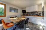 This modern dining area and kitchen features a rustic wooden dining table with plush velvet chairs, perfect for intimate gatherings.