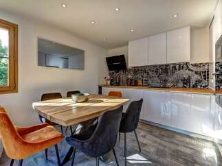 This modern dining area and kitchen features a rustic wooden dining table with plush velvet chairs, perfect for intimate gatherings.