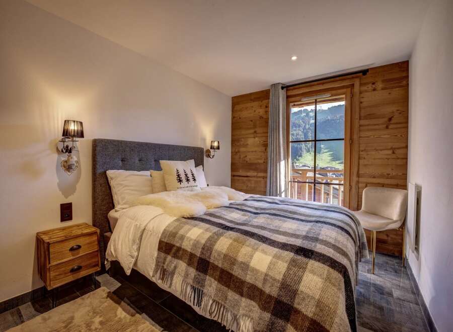 Experience cozy mountain living in this charming bedroom, featuring a plush bed adorned with a warm plaid blanket and soft pillows.