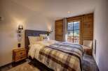 Experience cozy mountain living in this charming bedroom, featuring a plush bed adorned with a warm plaid blanket and soft pillows.