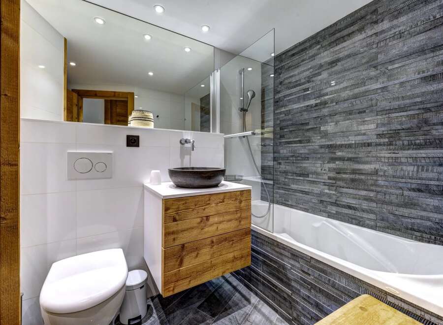 Experience modern mountain living in this beautifully appointed bathroom, featuring a sleek floating vanity with natural wood drawers and a striking stone vessel sink.