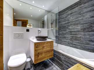 Experience modern mountain living in this beautifully appointed bathroom, featuring a sleek floating vanity with natural wood drawers and a striking stone vessel sink.