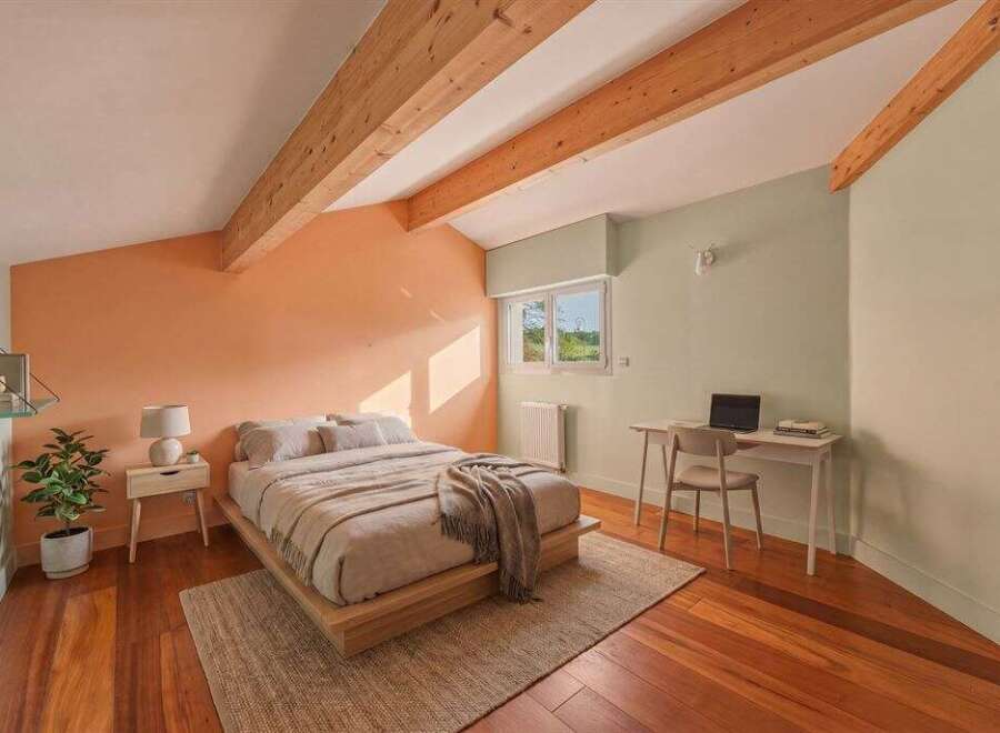 This stunning bedroom boasts a unique design with exposed wooden beams and a warm, inviting color palette.