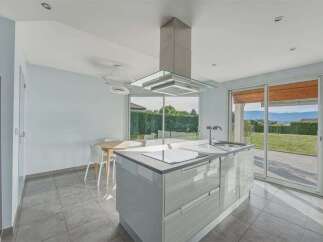 Experience modern living in this stunning kitchen featuring a sleek island with a built-in stovetop and sink.