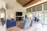 Step into this inviting living space, featuring a vaulted ceiling with exposed beams and abundant natural light.
