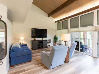 Step into this inviting living space, featuring a vaulted ceiling with exposed beams and abundant natural light.