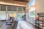Step into this stunning living space, featuring a vaulted ceiling with exposed wooden beams and expansive windows that flood the room with natural light.