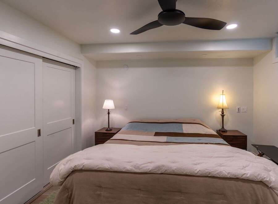 This cozy bedroom features a comfortable bed with a stylish quilt and bedside lamps, creating a warm and inviting atmosphere.