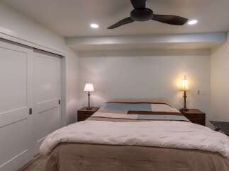 This cozy bedroom features a comfortable bed with a stylish quilt and bedside lamps, creating a warm and inviting atmosphere.