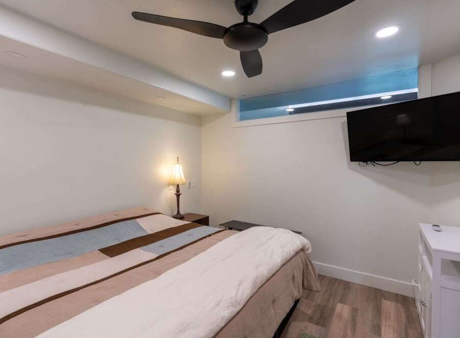 Discover the comfort of this inviting bedroom, featuring a stylish ceiling fan and a modern wall-mounted TV.