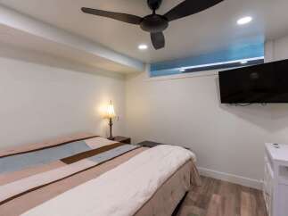 Discover the comfort of this inviting bedroom, featuring a stylish ceiling fan and a modern wall-mounted TV.
