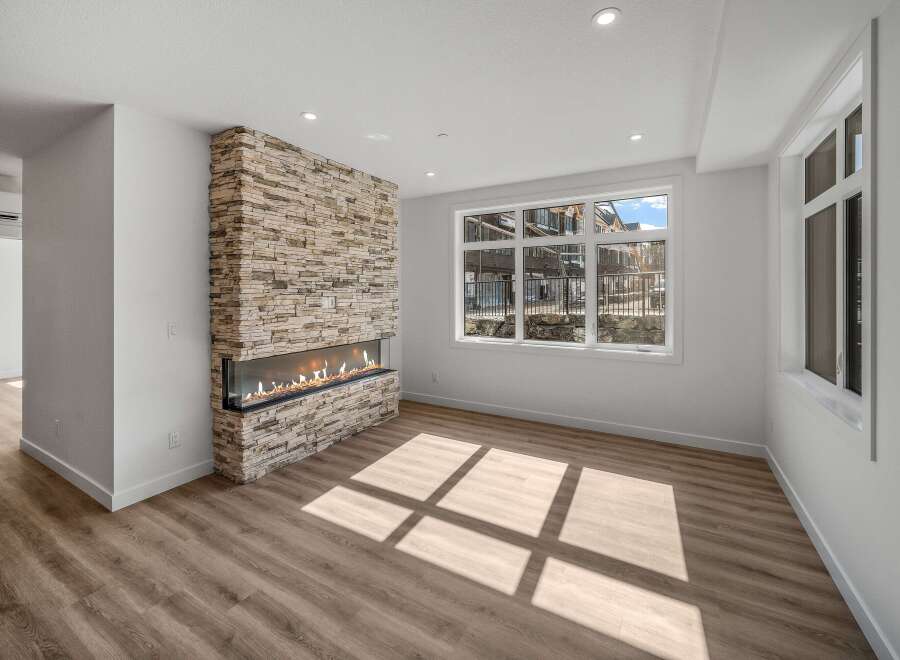 This stunning living space boasts a modern fireplace with a stone facade, creating a warm and inviting atmosphere.
