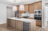 This modern kitchen boasts sleek wood cabinetry, a spacious island with a built-in wine cooler, and stainless steel appliances.