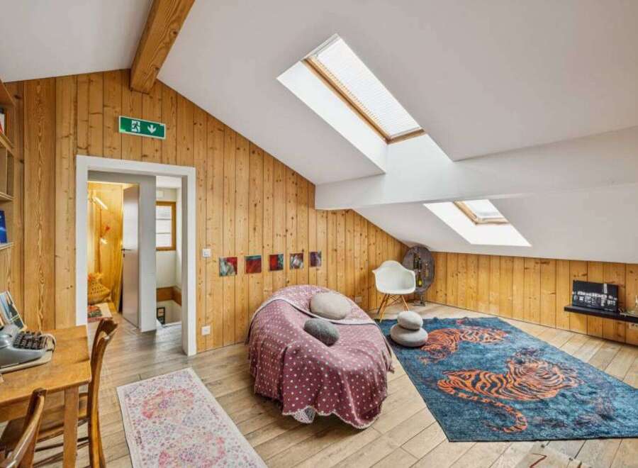 Discover the charm of this unique attic space, featuring stunning wooden paneling and a cozy seating area.