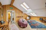 Discover the charm of this unique attic space, featuring stunning wooden paneling and a cozy seating area.