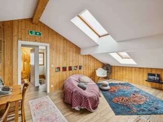 Discover the charm of this unique attic space, featuring stunning wooden paneling and a cozy seating area.