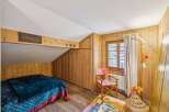 Discover the charm of this cozy bedroom featuring rustic wooden walls and a unique sloped ceiling.