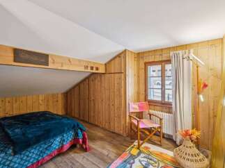 Discover the charm of this cozy bedroom featuring rustic wooden walls and a unique sloped ceiling.