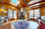 Step into this charming alpine property, featuring a cozy living room with a rustic wooden interior and a stunning stone fireplace.