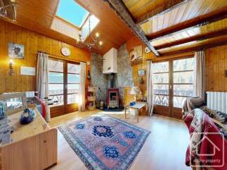 Step into this charming alpine property, featuring a cozy living room with a rustic wooden interior and a stunning stone fireplace.