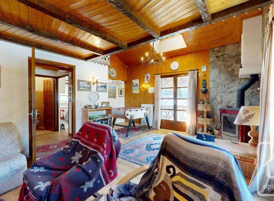 Step into this charming chalet-style living room, featuring a cozy ambiance with wooden paneling and a rustic fireplace.
