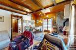 Step into this charming chalet-style living room, featuring a cozy ambiance with wooden paneling and a rustic fireplace.