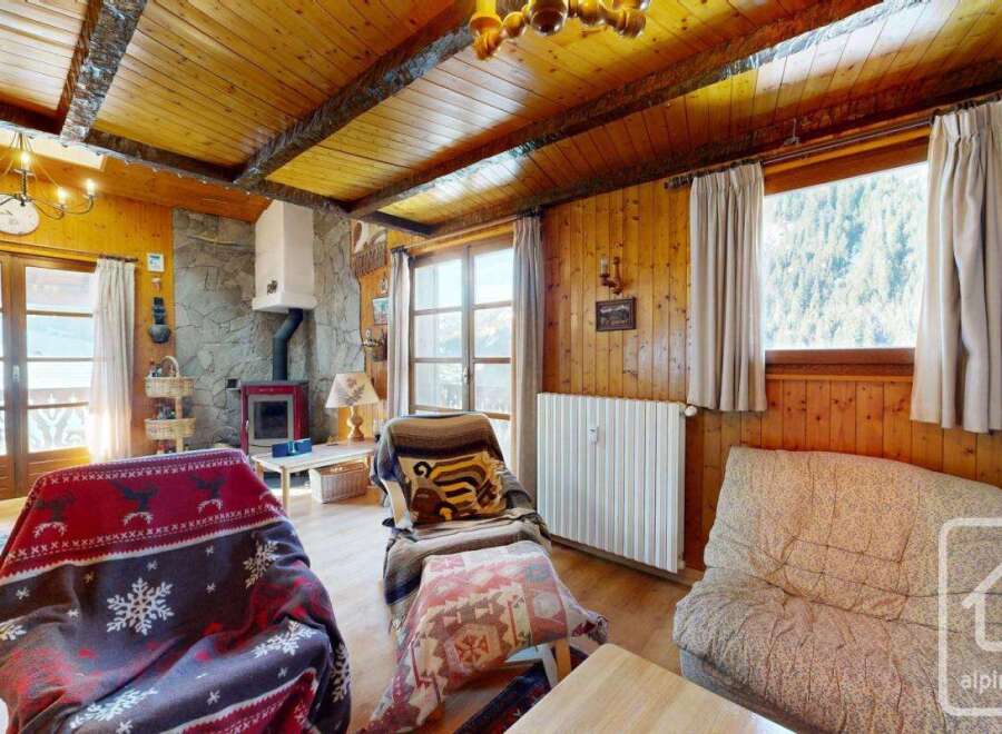 This charming property features a cozy living room with a stone fireplace and wooden paneling, creating a warm and inviting atmosphere.