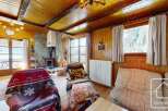 This charming property features a cozy living room with a stone fireplace and wooden paneling, creating a warm and inviting atmosphere.
