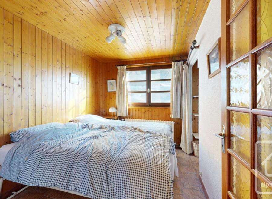 This charming bedroom features warm wood paneling on the walls and ceiling, creating a cozy and inviting atmosphere.