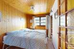 This charming bedroom features warm wood paneling on the walls and ceiling, creating a cozy and inviting atmosphere.