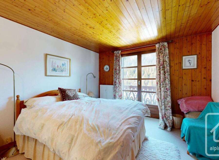 This charming bedroom features a cozy wooden ceiling and walls, creating a warm and inviting atmosphere.