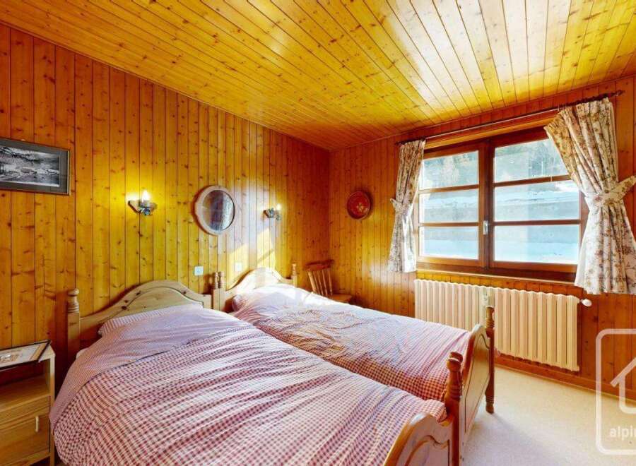 This charming bedroom features a cozy ambiance with its wooden paneling and warm lighting.