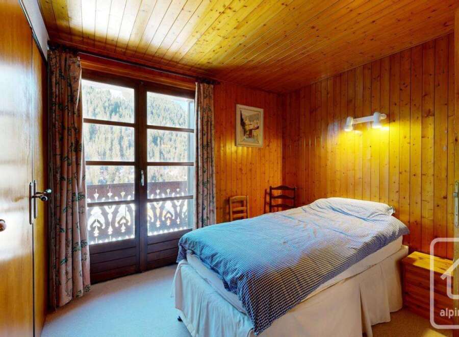 Discover the charm of this cozy bedroom featuring warm wooden paneling and a comfortable bed.