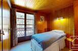 Discover the charm of this cozy bedroom featuring warm wooden paneling and a comfortable bed.