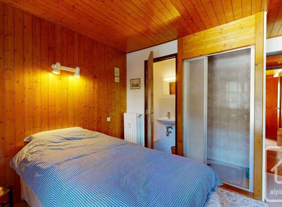 Discover the charm of this cozy bedroom featuring a warm wooden interior and a comfortable bed.