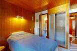 Discover the charm of this cozy bedroom featuring a warm wooden interior and a comfortable bed.