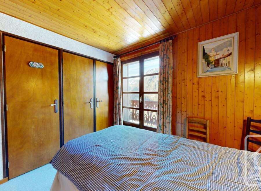 This charming bedroom features a cozy wooden ceiling and walls, creating a warm and inviting atmosphere.
