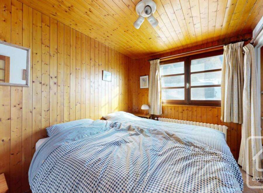 This cozy bedroom features warm wooden paneling on the walls and ceiling, creating a rustic and inviting atmosphere.