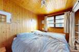 This cozy bedroom features warm wooden paneling on the walls and ceiling, creating a rustic and inviting atmosphere.
