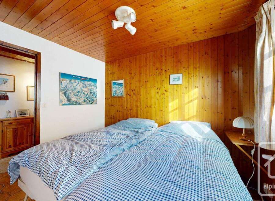 This cozy bedroom features a warm wooden ceiling and walls, creating a rustic and inviting atmosphere.